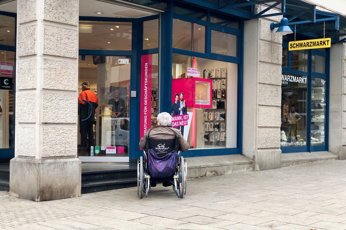 Person vor einer kleinen Treppe im Rollstuhl